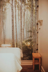 Massage table with white bedding in room with a forest mural at Dandle Spa that has the best couples massage in Chattanooga