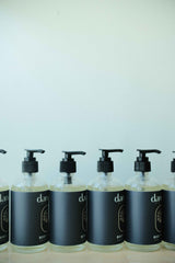 Row of black bottles with pump dispensers on a light blue background. Organic skincare products