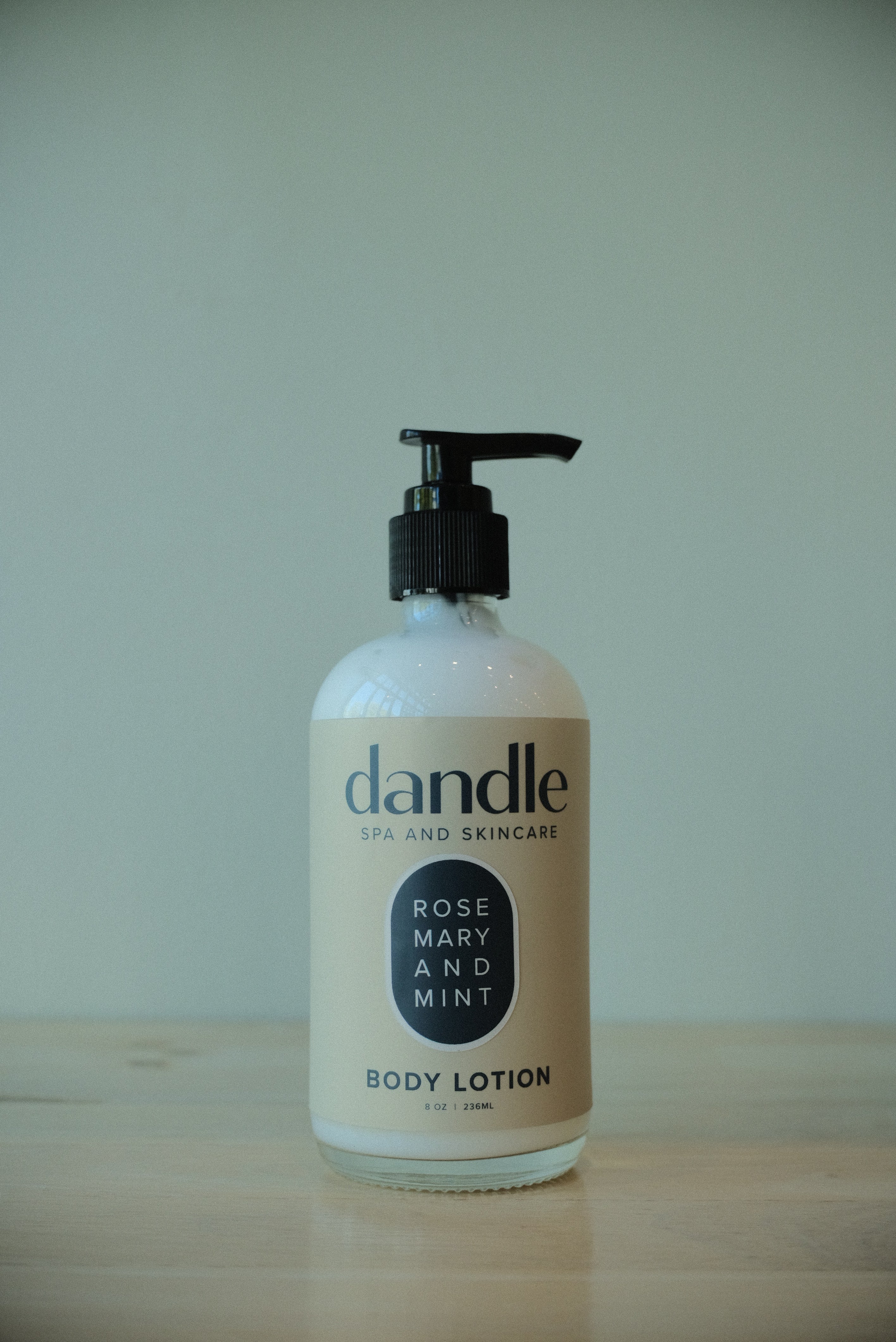 Dandle organic body lotion bottle on a wooden surface with a white background. all-natural lotion