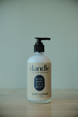 Dandle organic body lotion bottle on a wooden surface with a white background. all-natural lotion