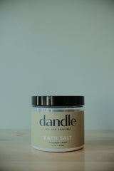 Jar of dandle bath salts on a wooden surface with a white background. Organic bath salts. 