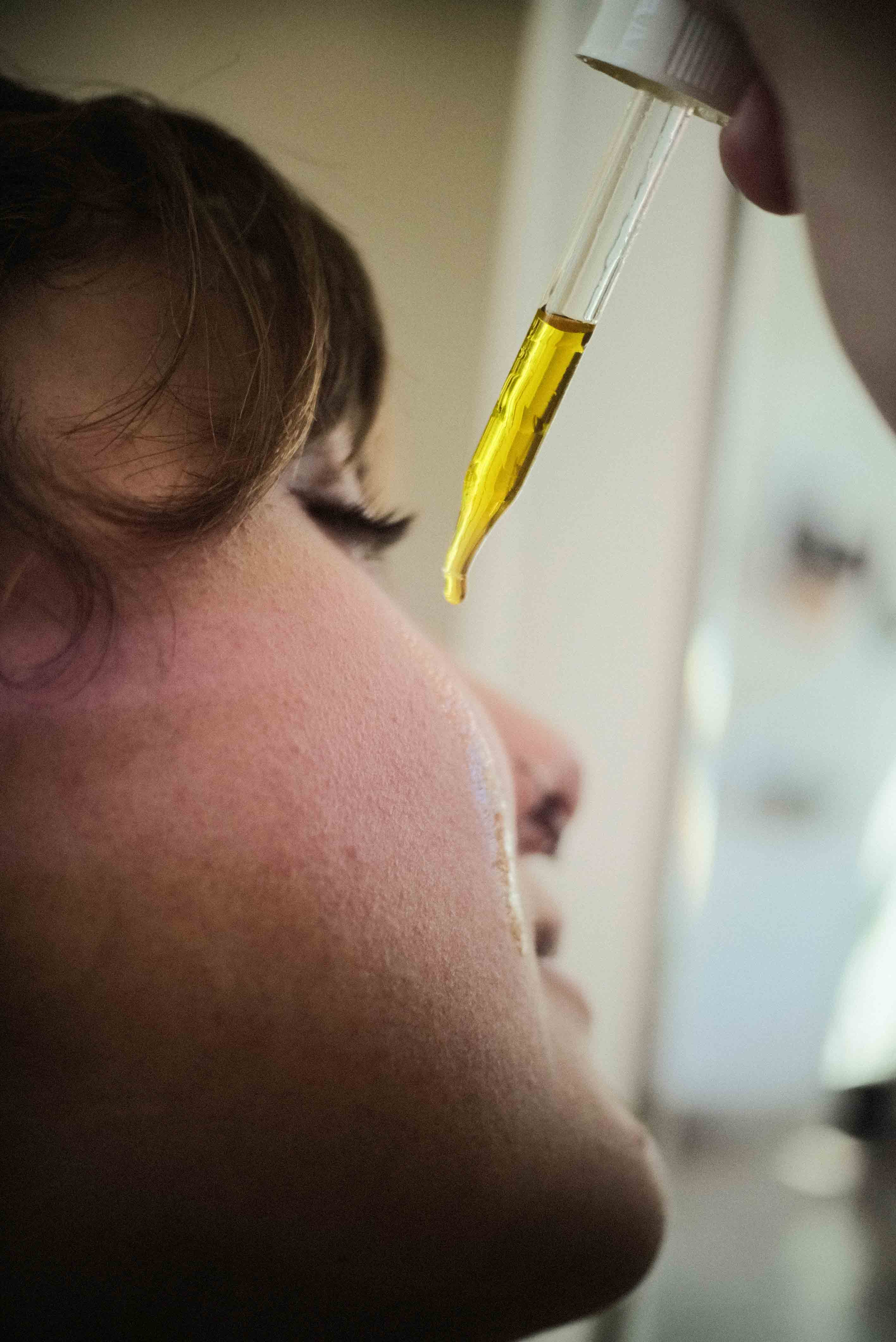 Female applying best waterless face oil serum to face with dropper. All natural, antioxidant serum from Dandle organice skincare line
