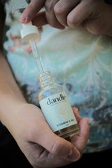 Hands holding Dandle Vitamin C glow oil with dropper top partly pulled out. natural waterless face oil. best organic vitamin c serum.