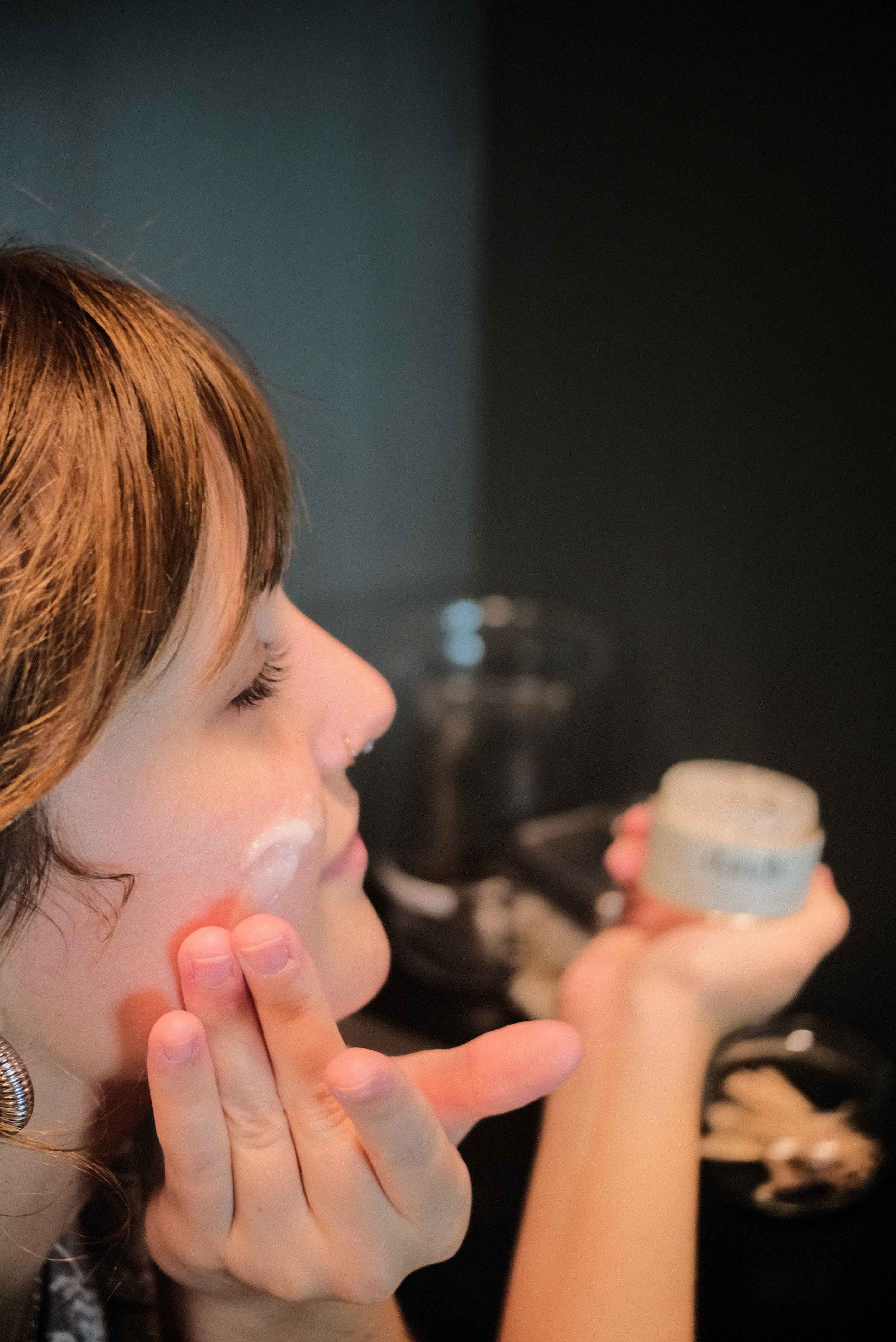 Female applying organic face cream to cheek. Best natural moisturizer for oily skin. 