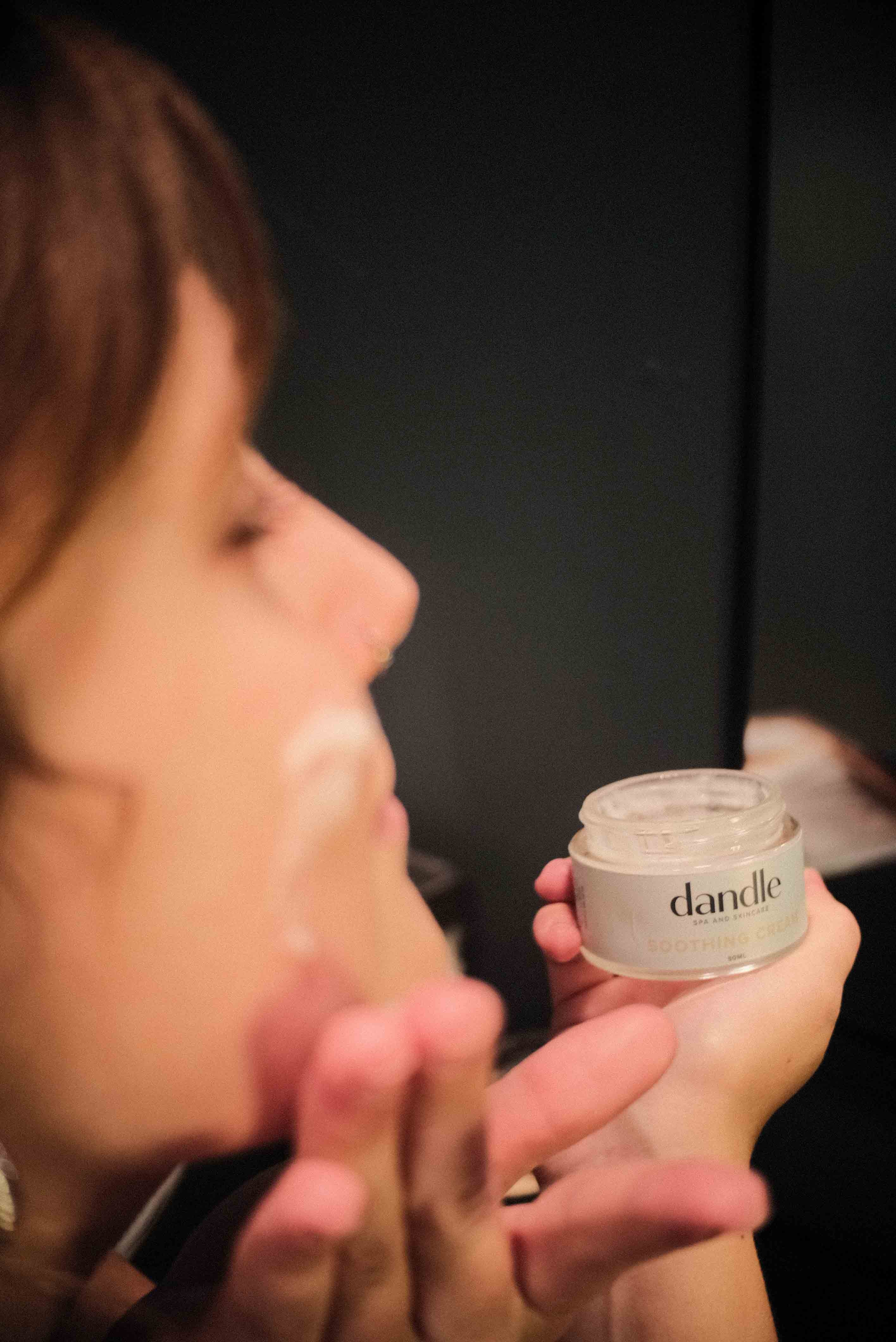 Female applying organic face moisturize to cheek. best face cream for dry skin