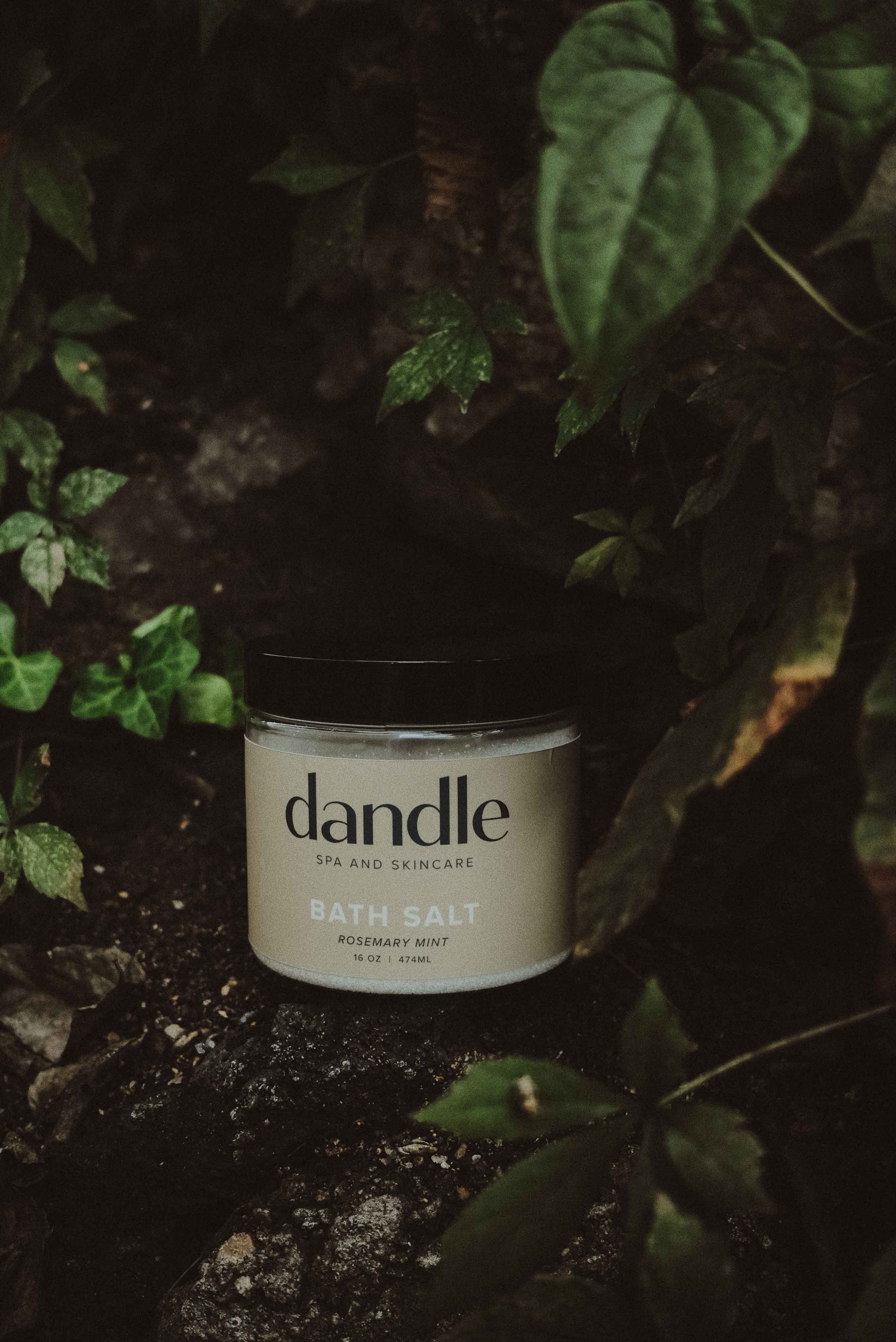 Jar of dandle all-natural bath salts surrounded by green foliage. Rosemary mint bath salt. Made in Tennessee