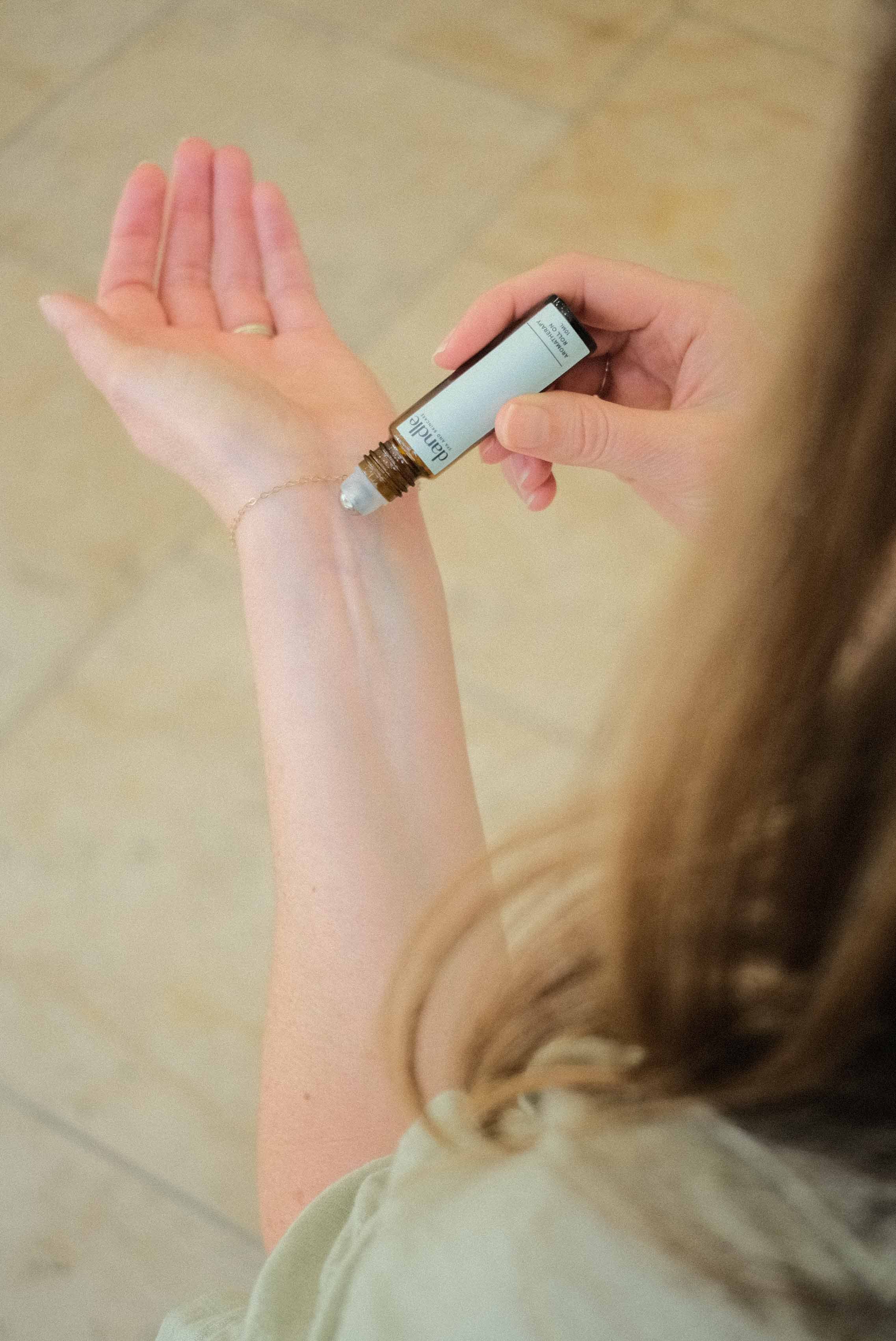 Female applying organic essential oil roller to wrist. Essential oils for headaches, hormones, breathing, sleep, stress, immune boosting,  