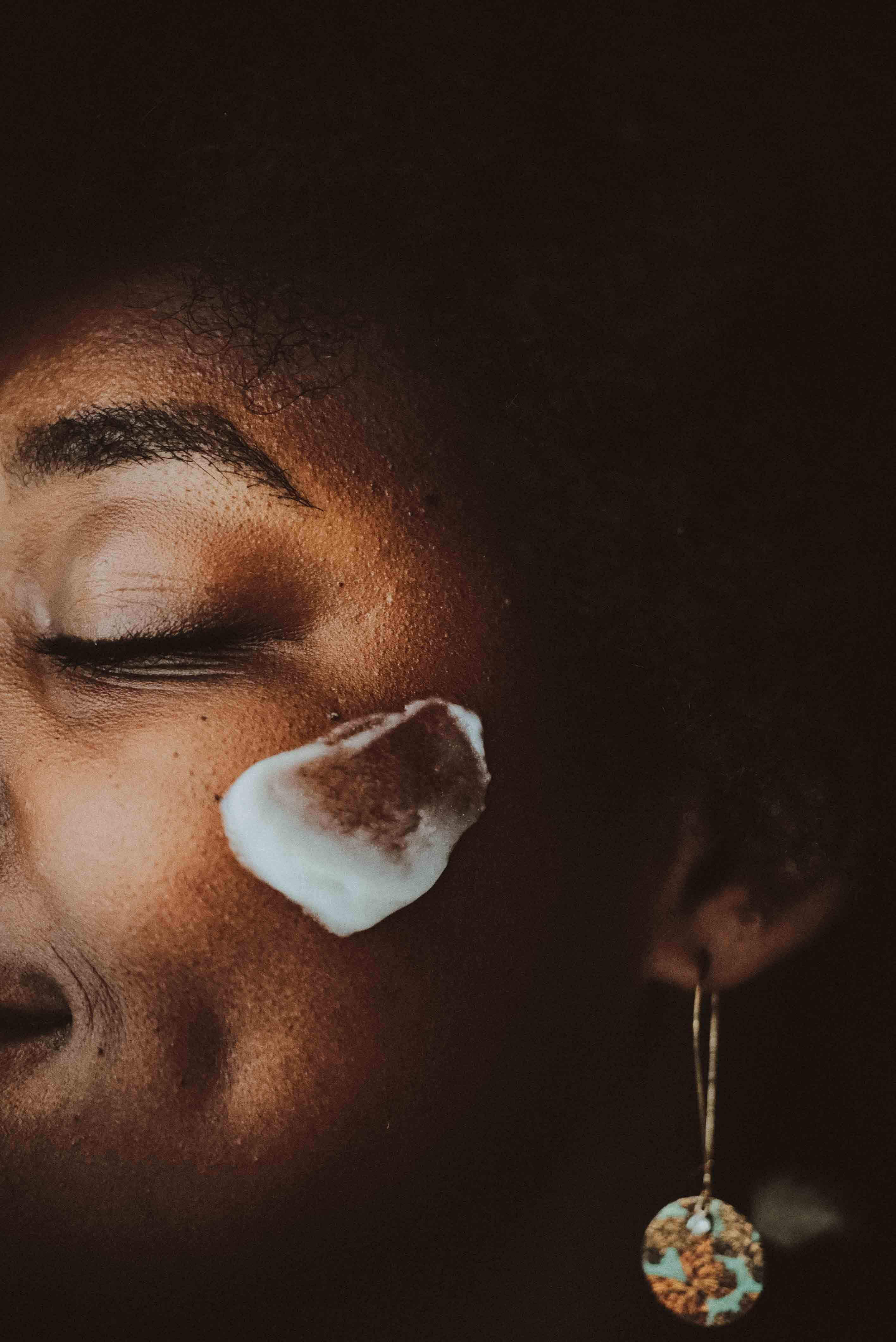 Close-up of a person with organic skincare on their face against a dark background. Local skincare line made in Chattanooga Tennessee. Smooths fine lines and wrinkles.