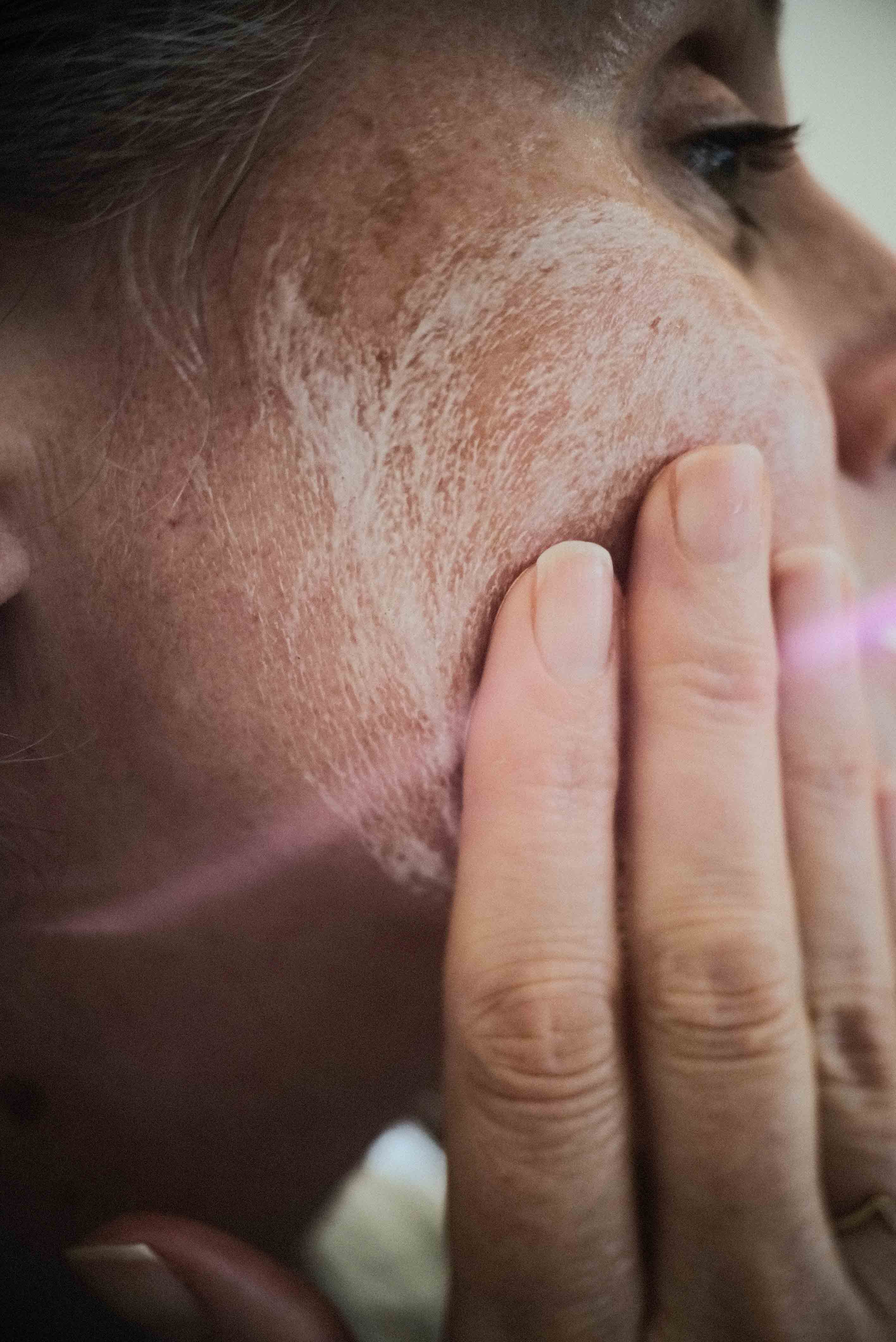 Close-up of female washing cheek with natural face wash. 