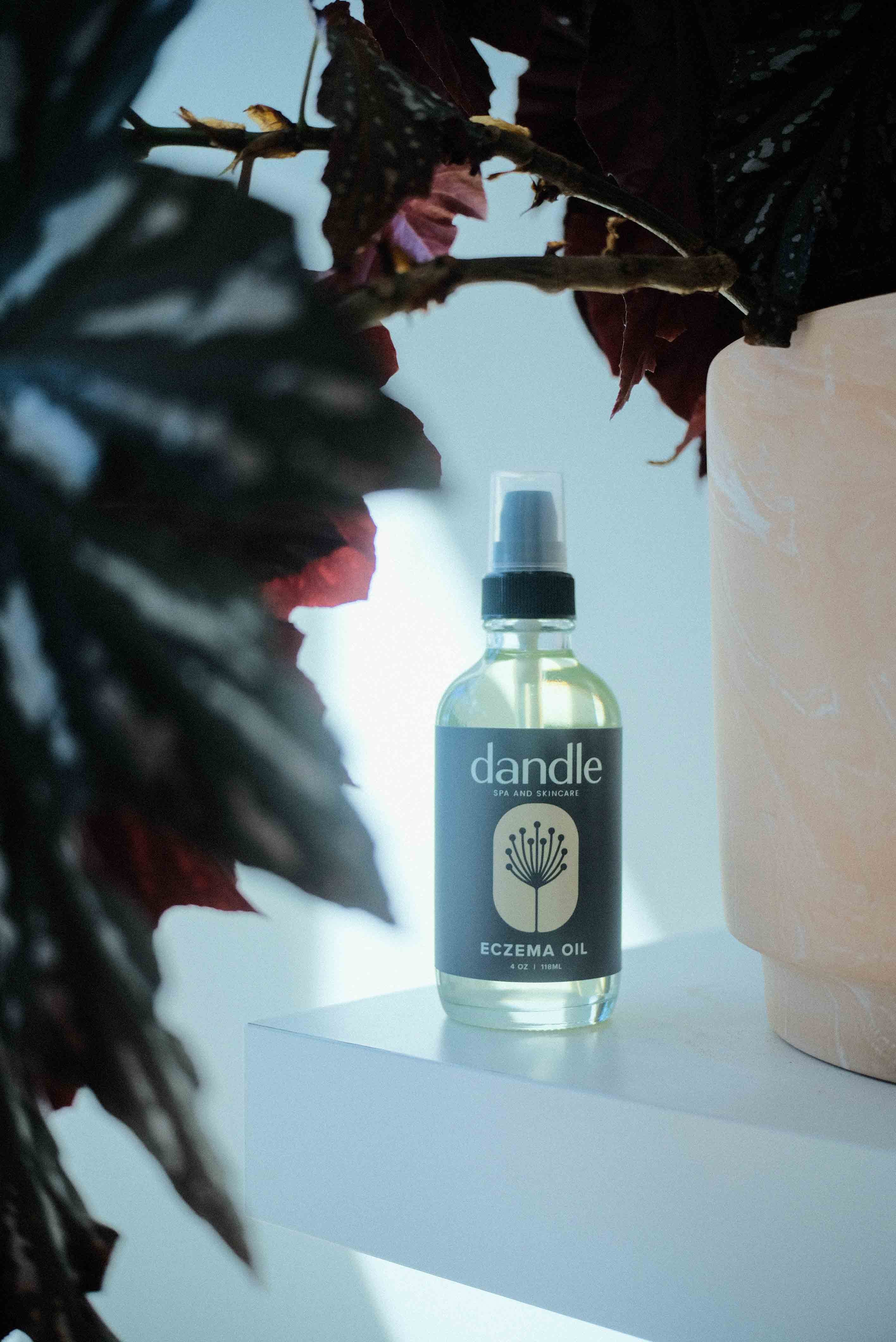 Eczema oil in glass bottle sitting  on white shelf, framed by plants. Local, Tennessee-made products, Chattanooga, TN. Shop local