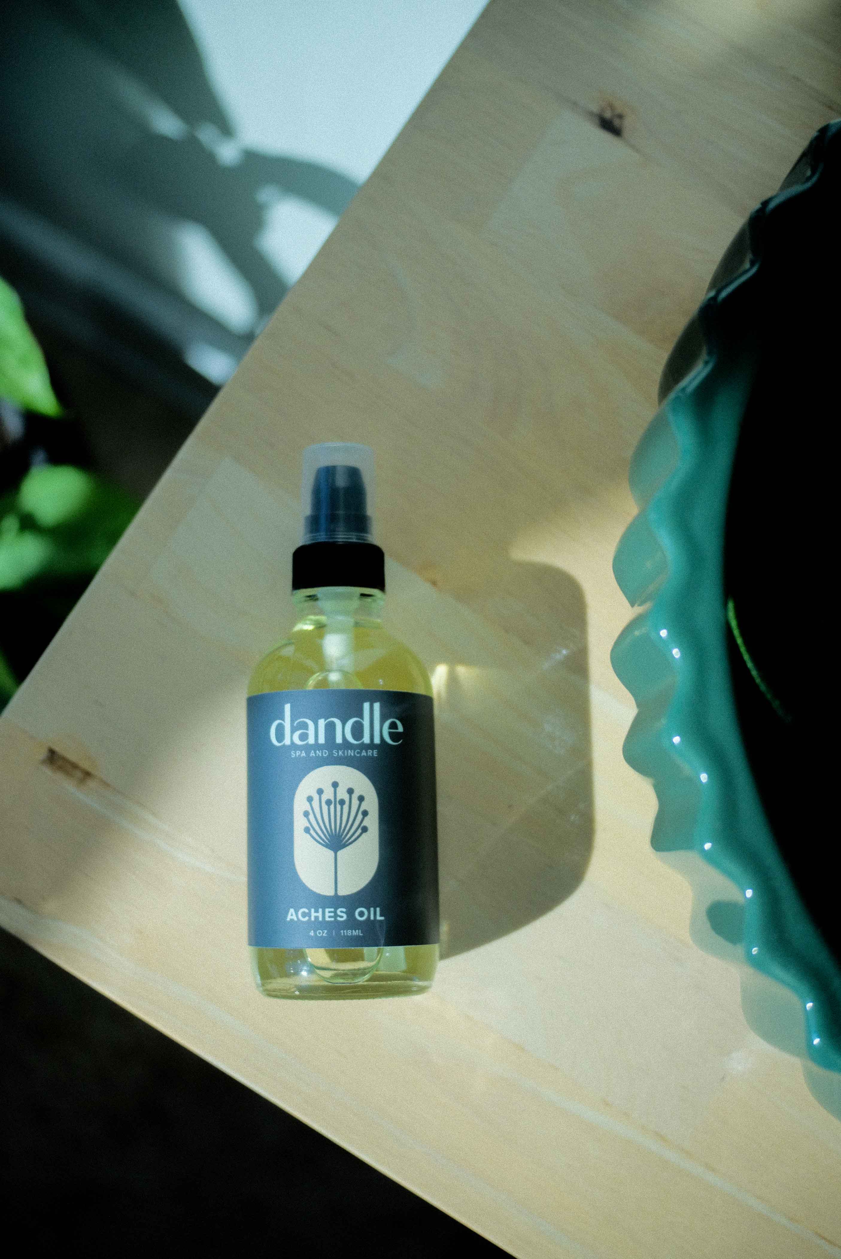 Body oil for muscle pain in glass bottle laying on wood surface. Soothes inflammation and increases circulation to eliminate body aches.