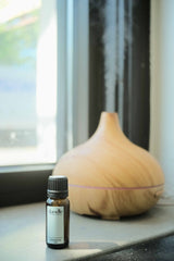 Aromatherapy oil bottle and diffuser on a windowsill with a blurred outdoor background. All-natural home fragrance. Young living