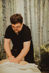Man giving a massage in a tranquil room with a forest background. Dandle spa has the best massage in Chattanooga, TN