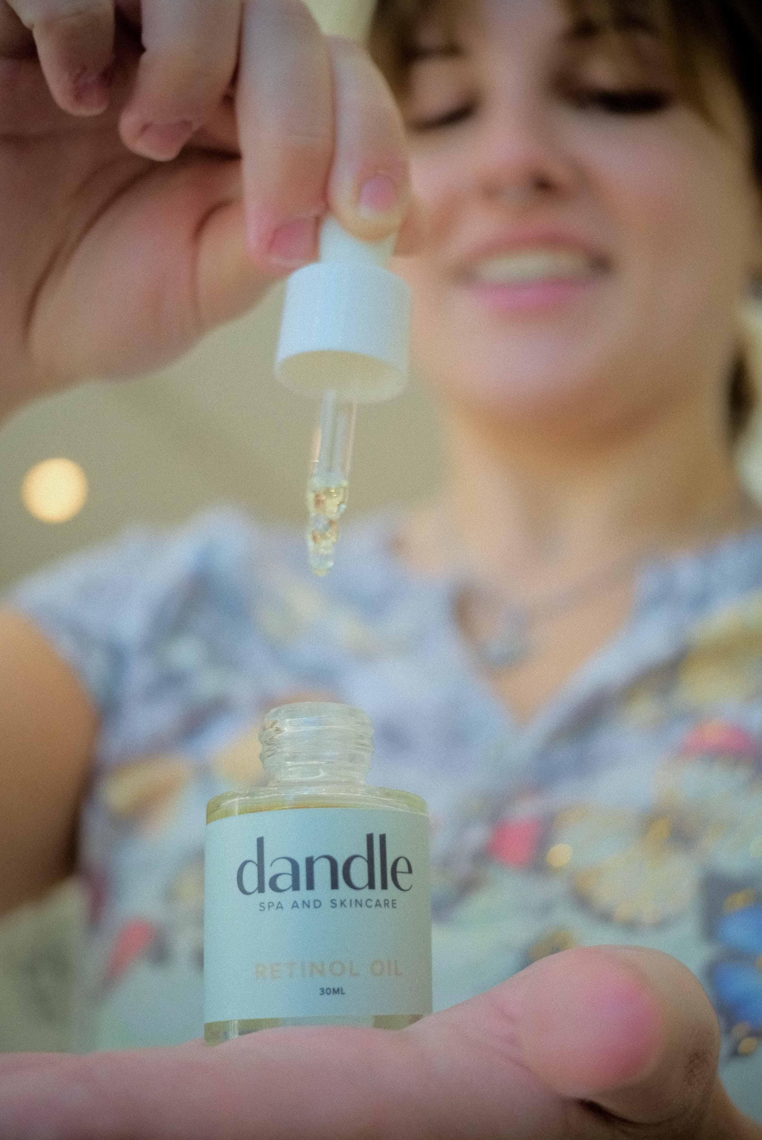 Girl holding all natural retinol oil bottle in hand and dropper in other hand. Best organic retinol serum to reduce fine lines and wrinkles