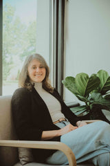 woman sitting in comfortable chair in storefront with windows and plants